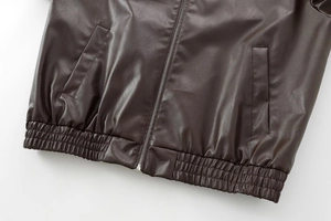 Detail view of brown faux leather jacket featuring elastic waistband and metal zipper