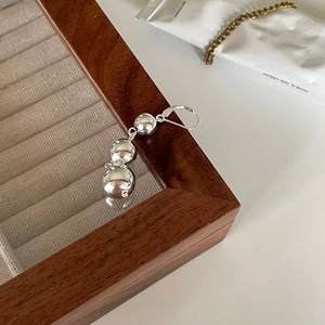 Macro detail of three graduated silver polished spheres on a modern minimalist ear cuff