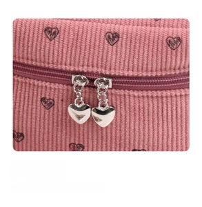 Detailed shot of pink corduroy pouch with dual heart-shaped metal zippers and pattern