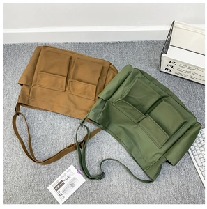 Detail of canvas shoulder bags with front pockets in brown and olive green colors