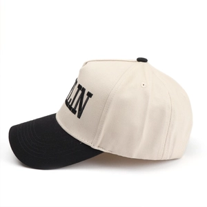 Close-up of beige and black baseball cap featuring 3D letter embroidery and curved brim