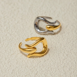 Abstract streamlined stainless steel rings in gold and silver on textured background
