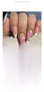 Detail of pink and white flower nail art with classic white French tips on denim backdrop