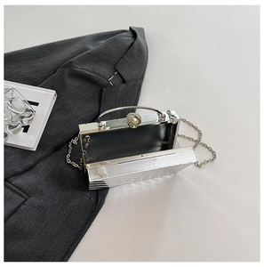 Detail view of silver acrylic evening clutch with wavy texture and pearl ball clasp