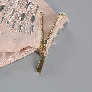 Macro shot of silver rhinestones and gold metal zipper on pink knit dress fabric