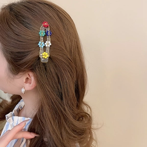 Detail of beaded flower hair clip with golden chains worn on wavy brown hair