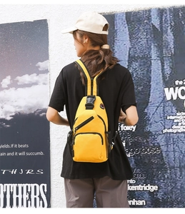 Detail view of yellow canvas chest bag with three zipper pockets and adjustable strap