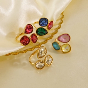 Detail von 14K vergoldeten Ringen mit bunten Kristallen auf champagnerfarbener Seide