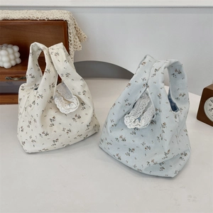 Detail of floral canvas tote bags with delicate lace trim in beige and light blue colors