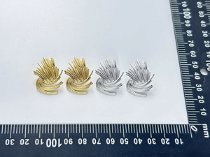 Macro detail of gold and silver textured earrings with fan-shaped sunburst pattern