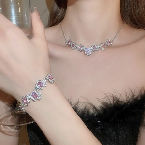 Detail of silver jewelry set with pink stones and zircons worn with black feather outfit