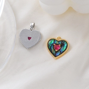 Detailed macro view of gold-plated heart charms with abalone shell and ruby inlay