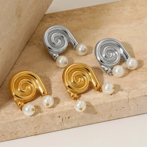 Boucles d'oreilles spirales dorées et argentées avec perles blanches sur fond pierre