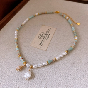 Detail of freshwater pearl and shell pendant necklace on soft beige textured fabric
