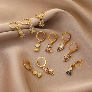 Golden cartoon animal hoop earrings with colorful zircon stones on beige fabric