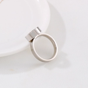 Detailed view of a silver stainless steel ring leaning on a white ceramic plate