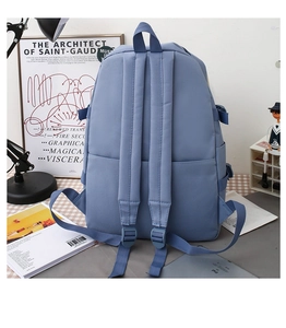 Detailed back view of a blue canvas backpack featuring dual straps and top handle for school