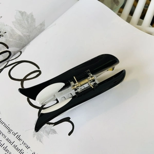 Close-up of a black and white penguin hair claw clip made of acetate on a white book page