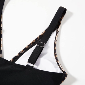 Close-up of adjustable straps with leopard print trim and silver metal rings on black swimsuit