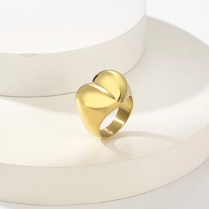 Detailed view of chunky heart-shaped gold-plated ring with polished metallic finish