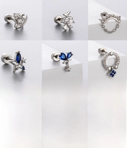 Macro detail of six silver titanium steel stud earrings with blue zircon butterflies and stars