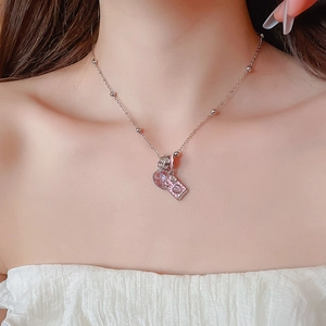 Detail of silver beaded necklace featuring a pink heart gem and rectangular pendant