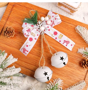 Close-up of white Christmas bells with red ribbon, pine needles and berries on wood