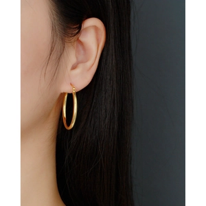 Close-up of a model wearing a minimalist polished gold sterling silver hoop earring