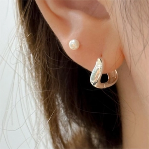 Détail de la boucle d'oreille incurvée en argent S925 et du clou perle sur l'oreille