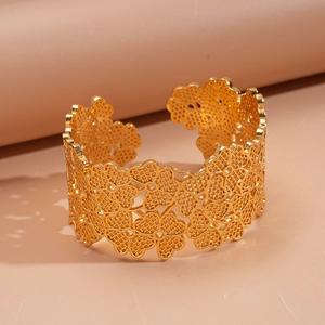 Détail macro du bracelet jonc doré avec motifs floraux ajourés et texture ciselée