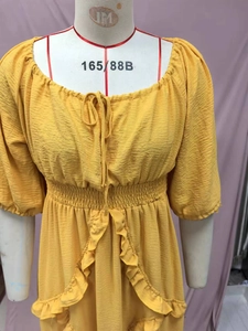 Detail view of yellow ruffled dress featuring textured pleated fabric and elastic waist