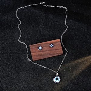 Elegant silver evil eye jewelry set with necklace and stud earrings on dark wood