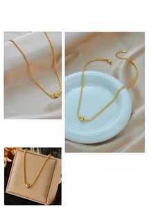 Detailed view of gold twisted chain necklace with a polished bead pendant on silk