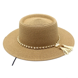 Détail du chapeau de paille plat avec chaîne dorée, perles et glands élégants