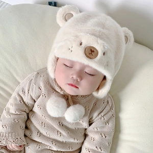 Dettaglio del cappello di peluche per neonati con orecchie d'orso e pompon bianco