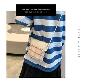 Detail of canvas crossbody bag with pink plaid pattern and cream strap on model