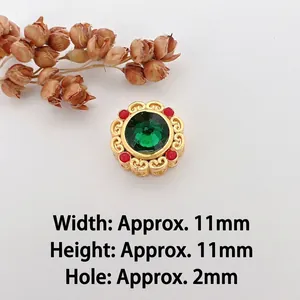 Macro detail of 11mm gold bead with green gemstone and red accents for DIY jewelry