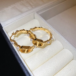 Macro shot of gold-plated hoop earrings featuring white pearls and signature CD logo