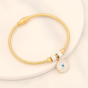 Golden snake chain bracelet with evil eye pendant and crystal accents on a white dish