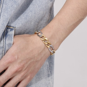 Gros plan d'un bracelet gourmette bicolore or et argent au poignet avec veste en jean