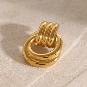 Macro shot of polished gold-finished vintage thick hoop earring on sand texture background