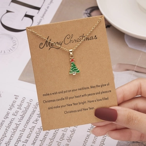 Details einer Goldkette mit grünem Emaille-Weihnachtsbaum auf einer Festkarte