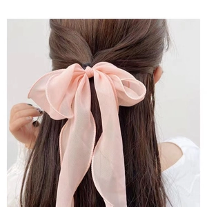 Pink ribbon bow hair accessory with long streamers worn by a model on a white background