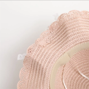 Detail of pink straw sun hat showing fine woven texture and delicate lace trimming