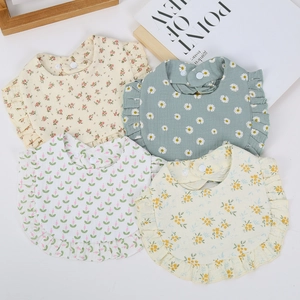 Detailed view of four cotton gauze baby bibs with ruffle edges and floral patterns