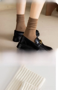 Détail des chaussettes en coton côtelé marron et crème portées avec des mocassins