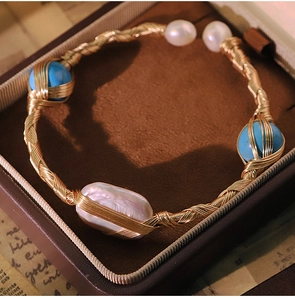 Detailed shot of handmade gold wire-wrapped bracelet with baroque pearls and turquoise