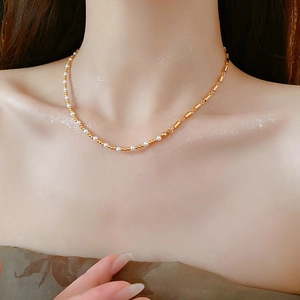 Detail of elegant gold chain necklace with white pearls on woman's collarbone