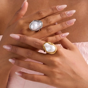 Detailed view of gold and silver titanium steel rings with baroque pearls worn by a model
