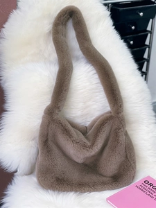 Close-up of soft brown faux fur shoulder bag texture on a white plush rug background